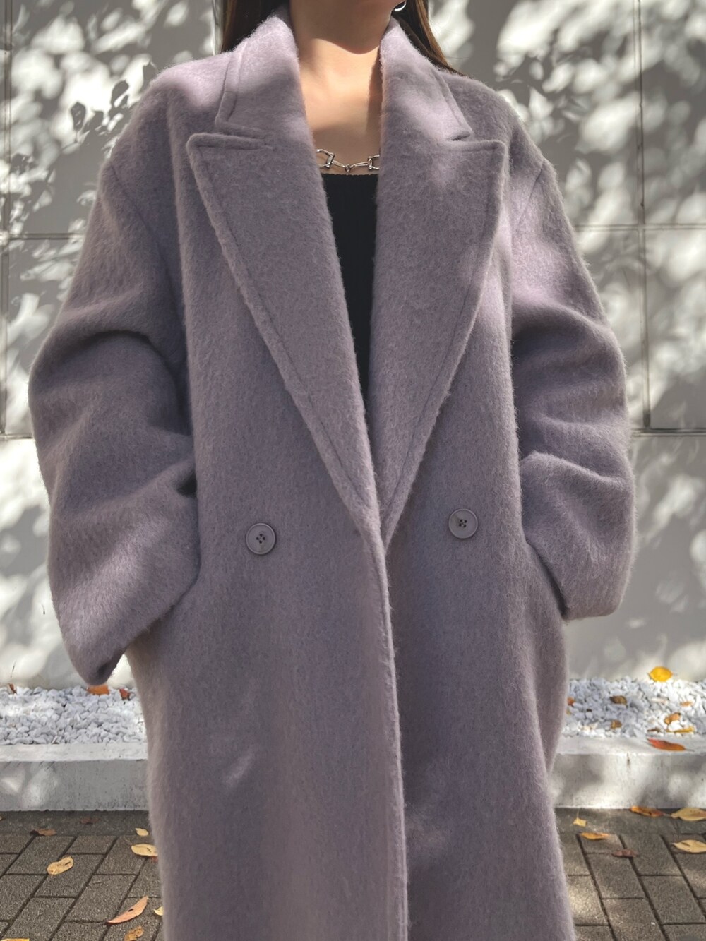 パープル系のチェスターコート、ブラック系のワンピース、ブラック系のブーツを着用したレディースの冬コーディネートの4枚目の写真