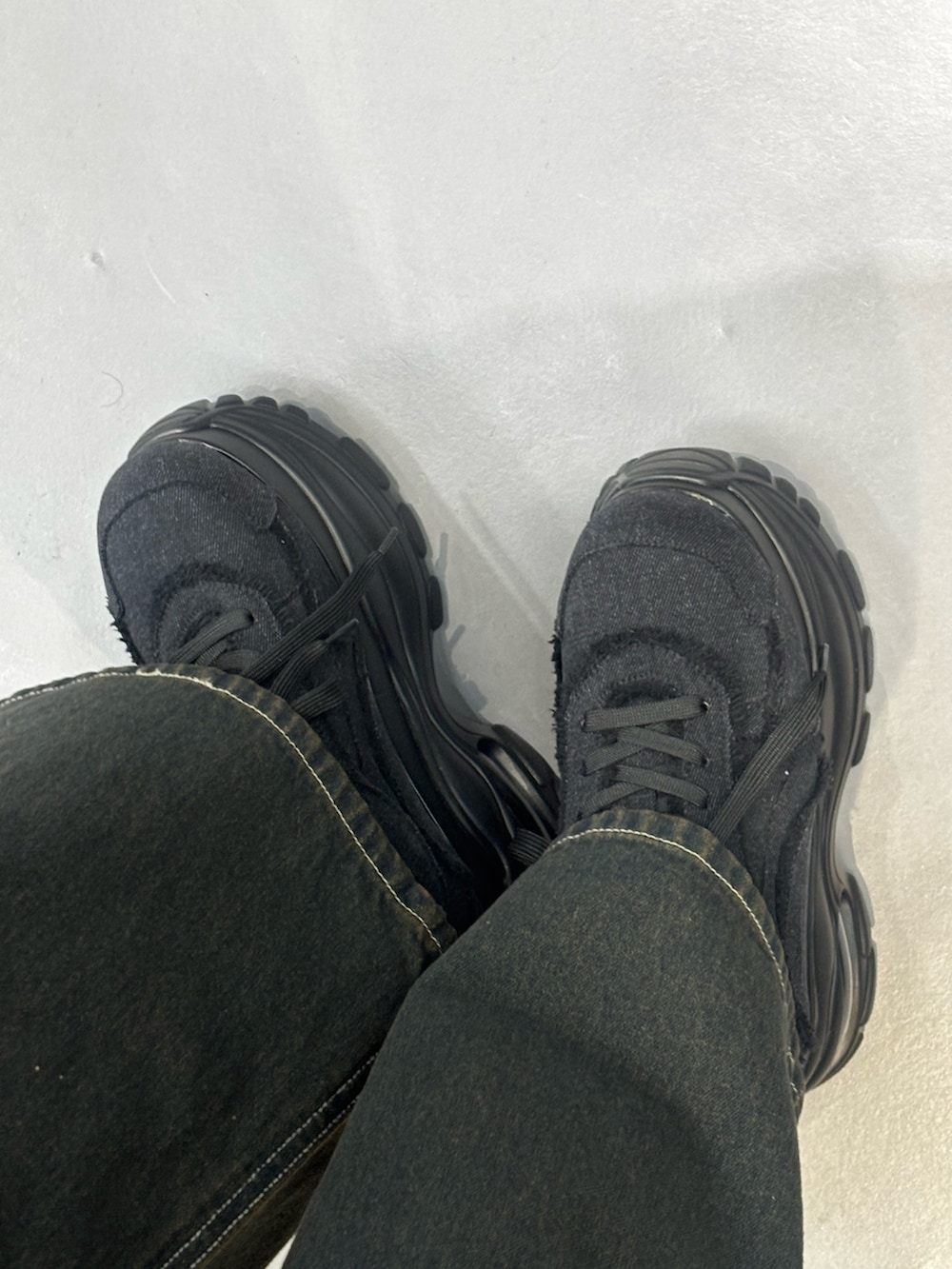 ベージュ系のデニムパンツ、ブラック系のシャツ/ブラウス、ブラック系のスニーカーを着用したレディースの冬コーディネートの6枚目の写真