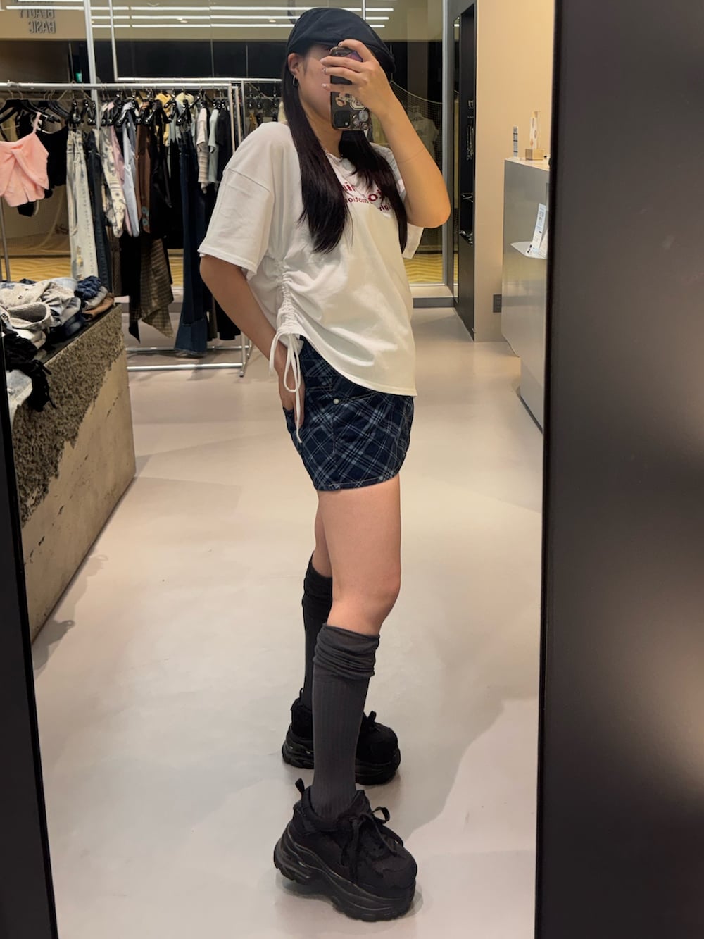 ブラック系のスニーカー、ホワイト系のTシャツ/カットソー、ブルー系のスカートを着用したレディースの春コーディネートの2枚目の写真
