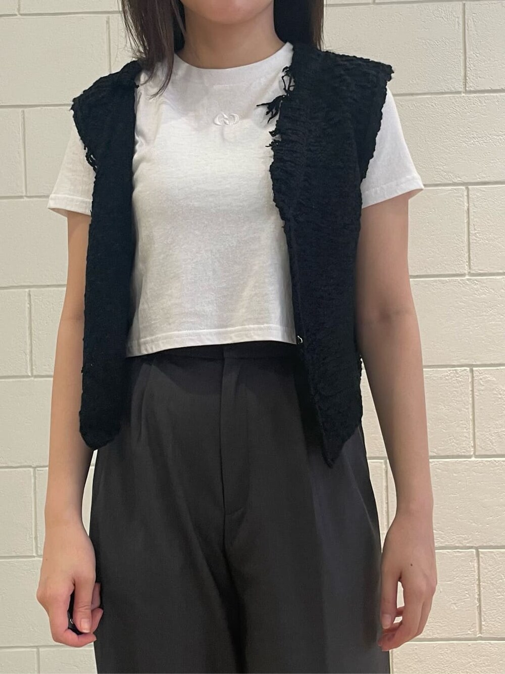 ブラック系のサンダル、ホワイト系のTシャツ/カットソー、ブラック系のベストを着用したレディースの夏コーディネートの3枚目の写真