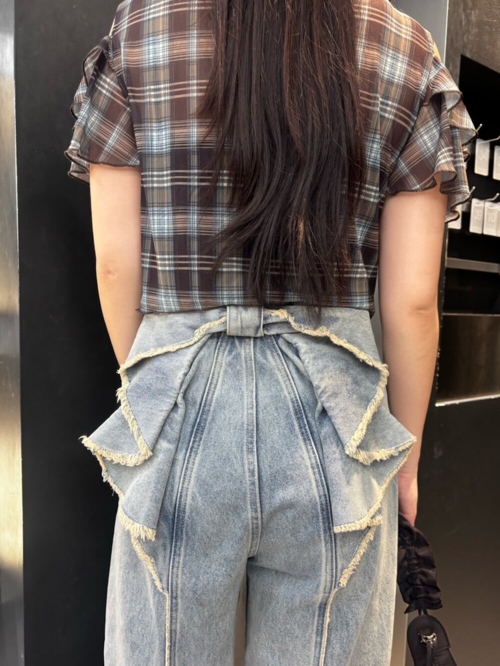 ブラック系のスニーカー、ブルー系のデニムパンツ、ブラック系のショルダーバッグを着用したレディースの夏コーディネートの7枚目の写真