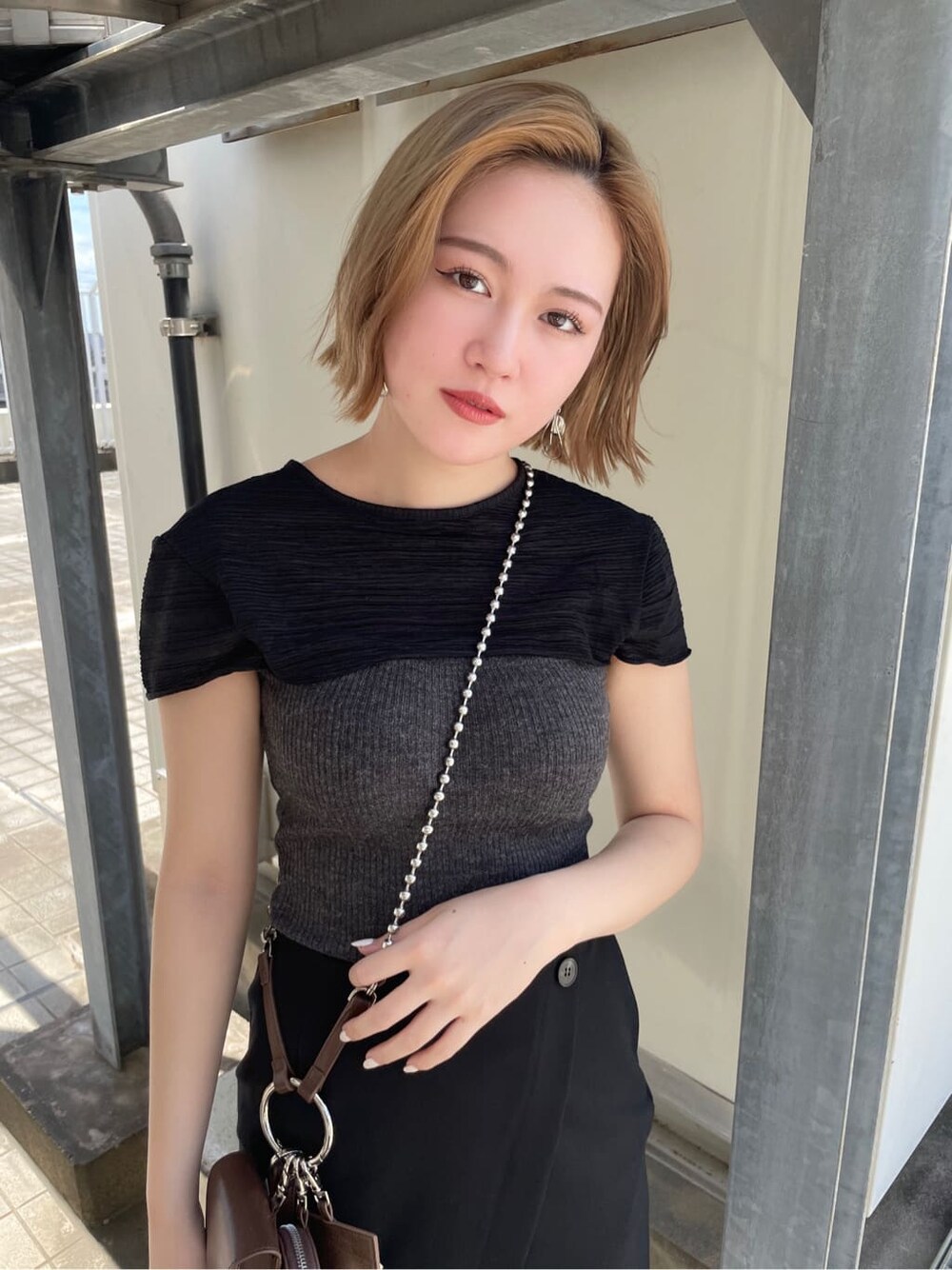 ブラウン系のハンドバッグ、ブラック系のサンダル、ブラック系のスカートを着用したレディースの夏コーディネートの2枚目の写真