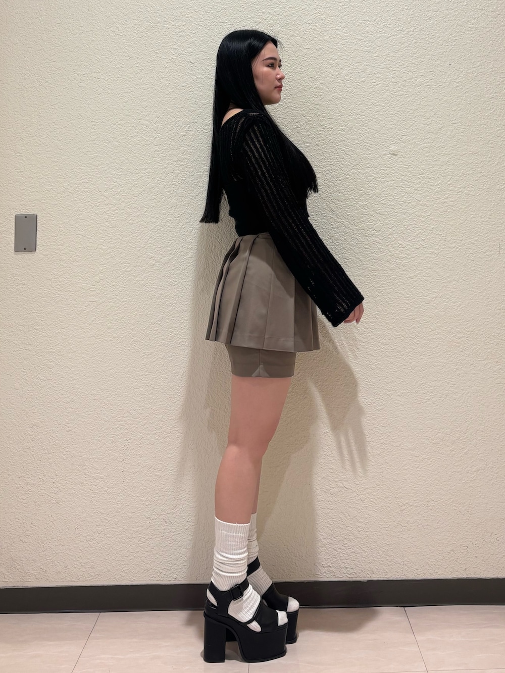 ブラック系のサンダル、ベージュ系のスカート、ブラック系のニット/セーターを着用したレディースの春コーディネートの2枚目の写真