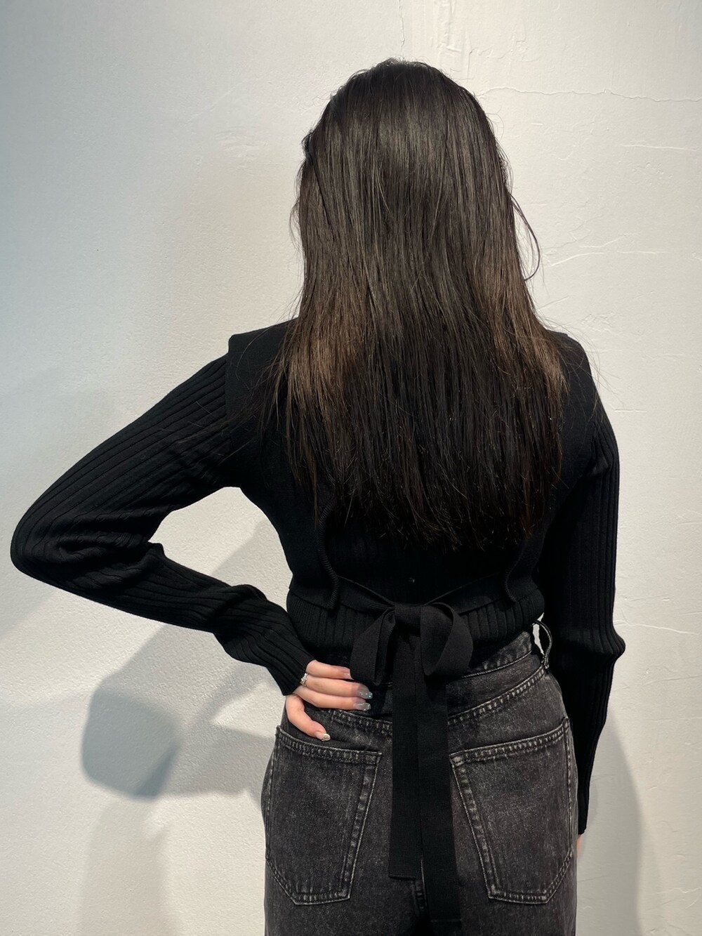 ブラック系のデニムパンツ、ブラック系のニット/セーター、シルバー系のブーツを着用したレディースの秋コーディネートの7枚目の写真