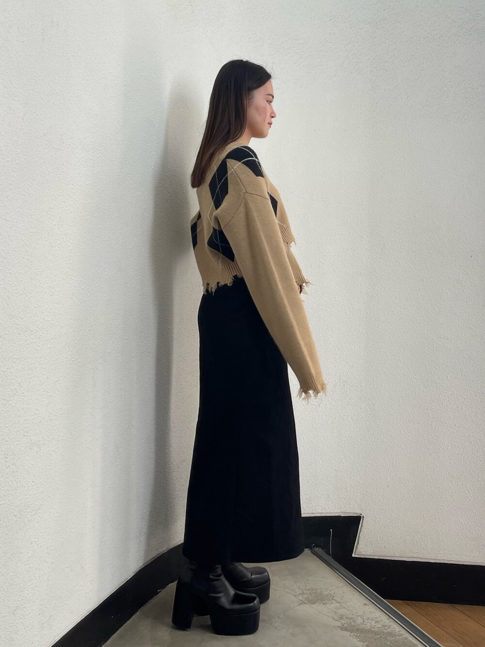 ブラック系のスカート、ブラック系のブーツ、その他のニット/セーターを着用したレディースの秋コーディネートの2枚目の写真