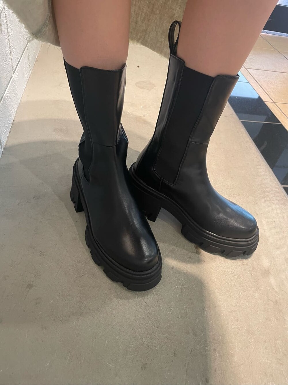 ホワイト系のスカート、ブラック系のブーツ、その他のTシャツ/カットソーを着用したレディースの夏コーディネートの7枚目の写真