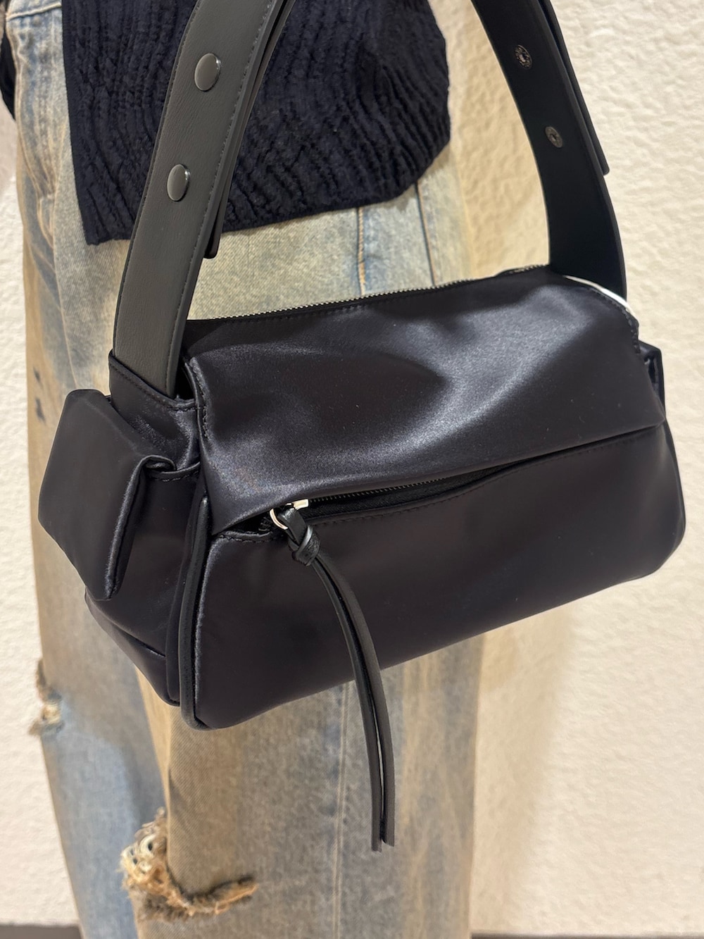 ブラック系のブーツ、ブラック系のハンドバッグ、ブルー系のデニムパンツを着用したレディースの春コーディネートの7枚目の写真