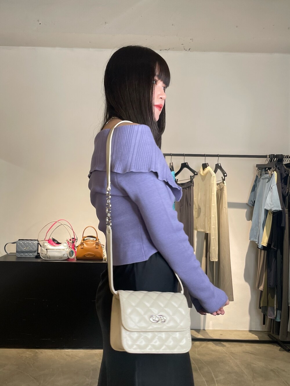 ブラック系のスカート、ブラック系のブーツ、パープル系のニット/セーターを着用したレディースの春コーディネートの5枚目の写真