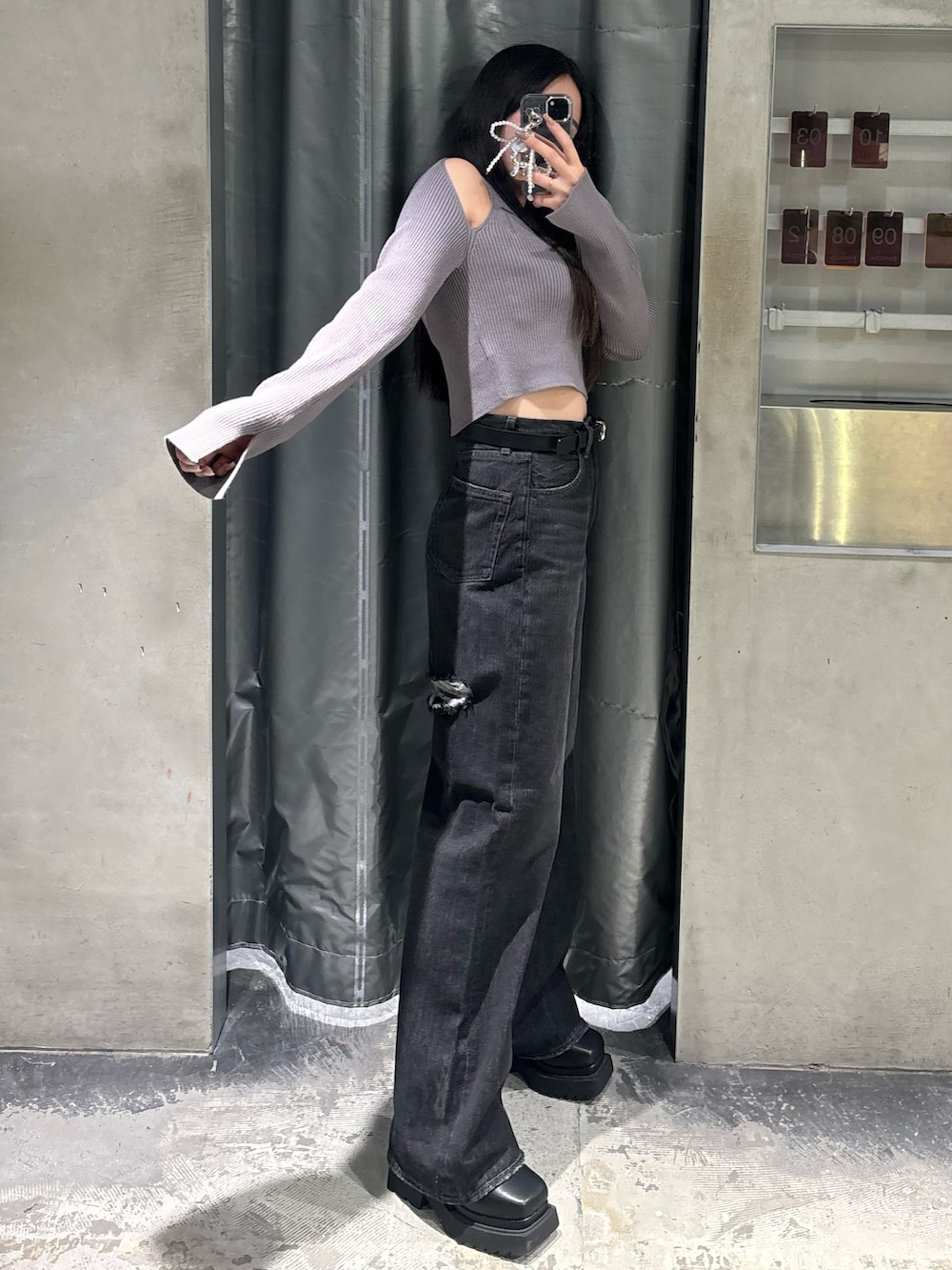 ブルー系のデニムパンツ、グレー系のニット/セーター、ブラック系のブーツを着用したレディースの秋コーディネートの2枚目の写真