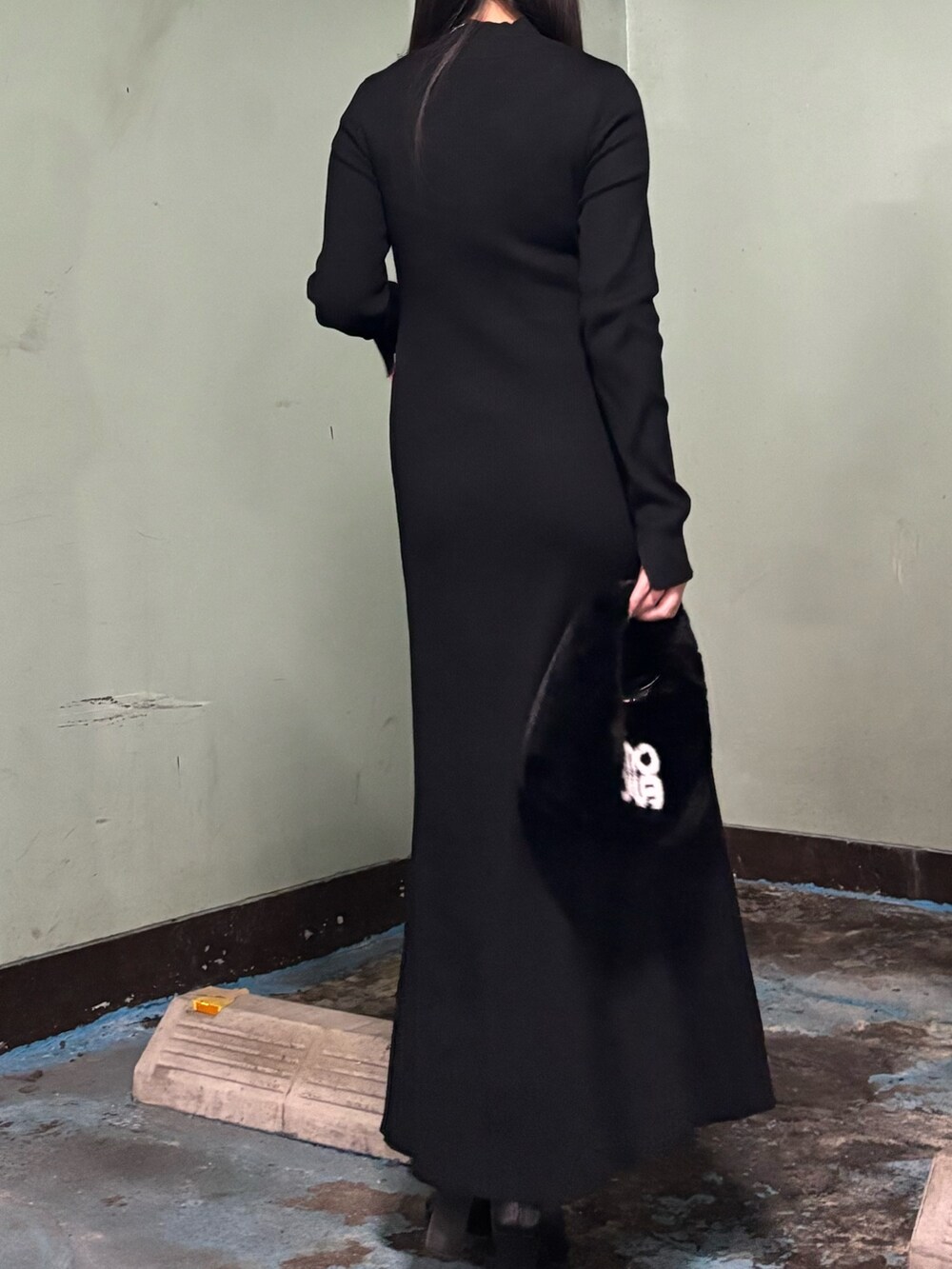 ブラック系のハンドバッグ、ブラック系のワンピース、ブラック系のブーツを着用したレディースの冬コーディネートの3枚目の写真