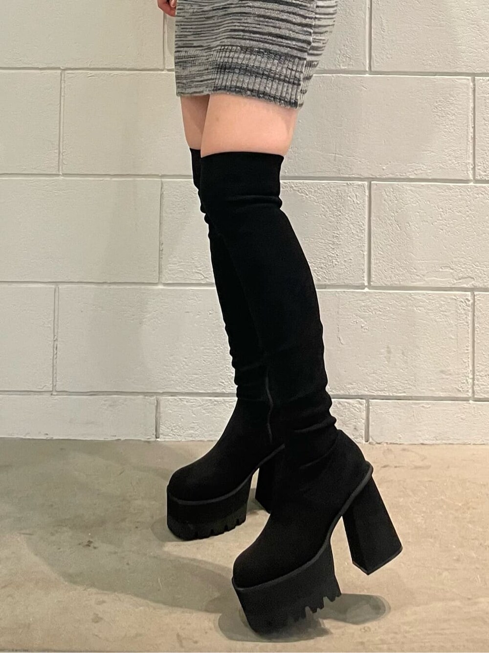 ブラック系のスカート、ブラック系のニット/セーター、ブラック系のブーツを着用したレディースの夏コーディネートの7枚目の写真