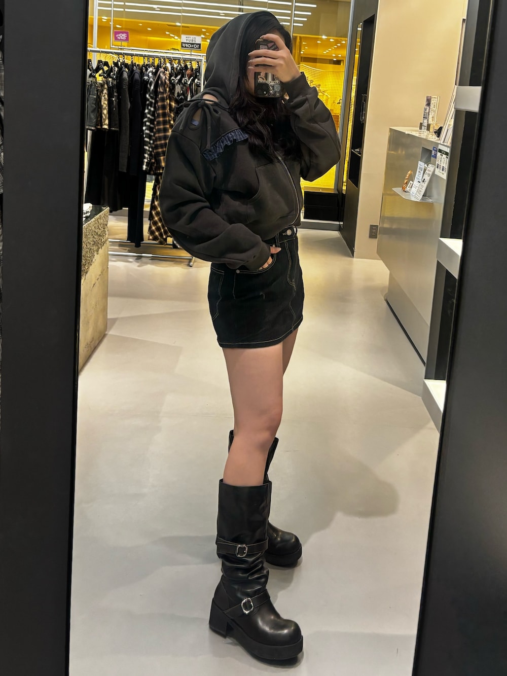 ブラック系のブーツ、ブラック系のパーカー、ブルー系のスカートを着用したレディースの冬コーディネートの2枚目の写真