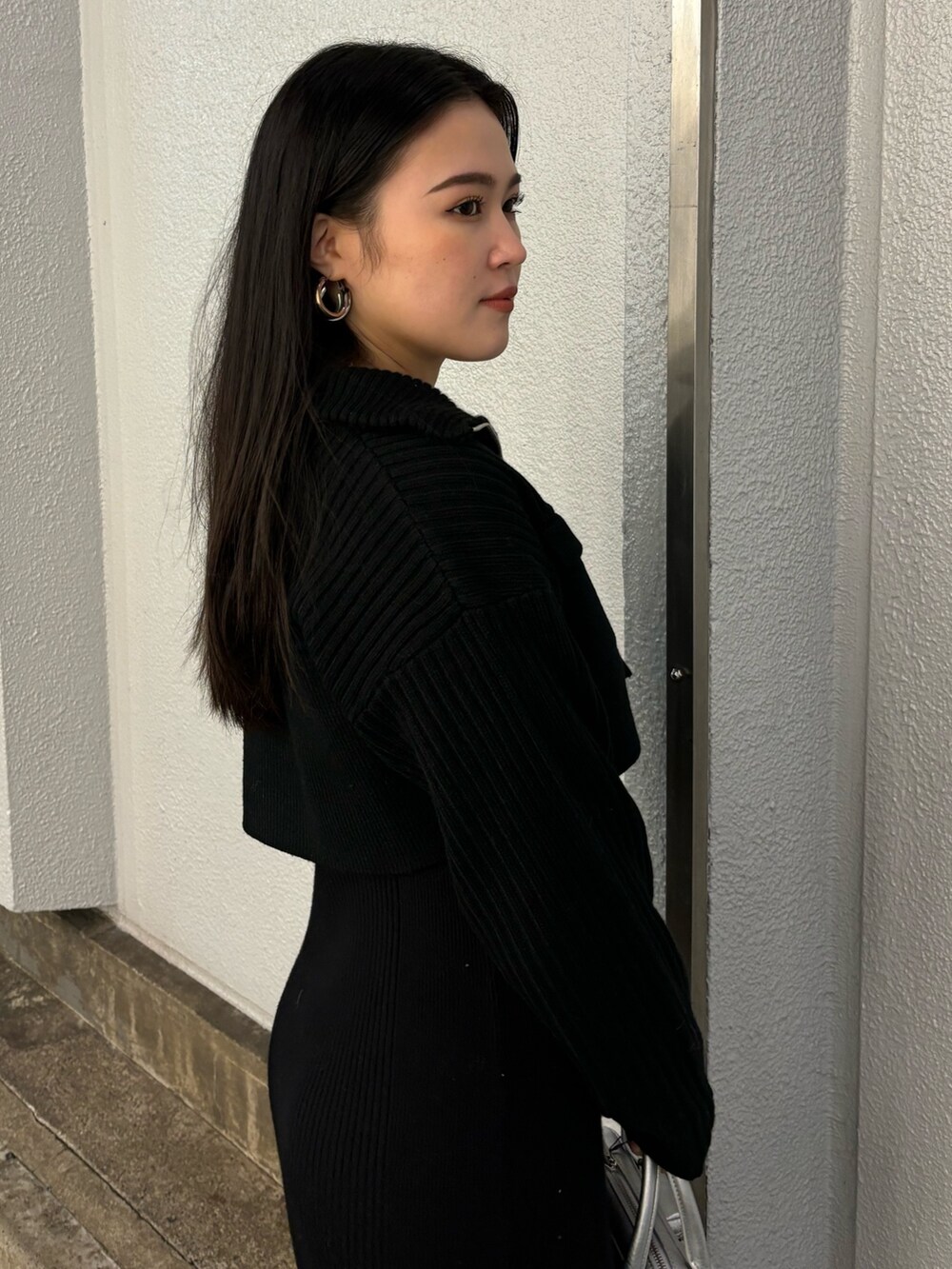 ブラック系のワンピース、ブラック系のブーツ、シルバー系のハンドバッグを着用したレディースの秋コーディネートの5枚目の写真