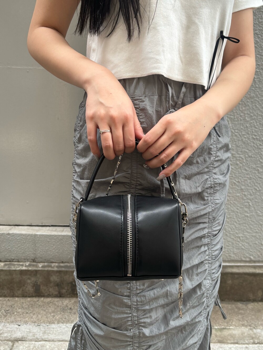 ブラック系のサンダル、ホワイト系のTシャツ/カットソー、ブラック系のハンドバッグを着用したレディースの夏コーディネートの5枚目の写真