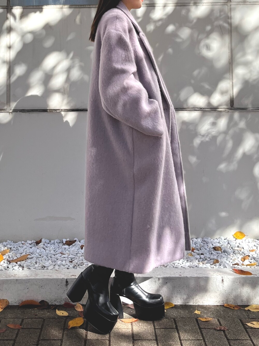 パープル系のチェスターコート、ブラック系のワンピース、ブラック系のブーツを着用したレディースの冬コーディネートの2枚目の写真