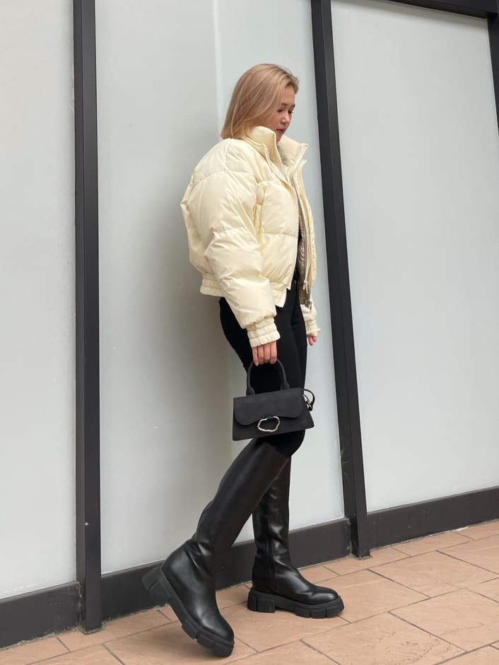 ブラック系のブーツ、ホワイト系のダウンジャケット/コート、ブラック系のデニムパンツを着用したレディースの冬コーディネートの2枚目の写真