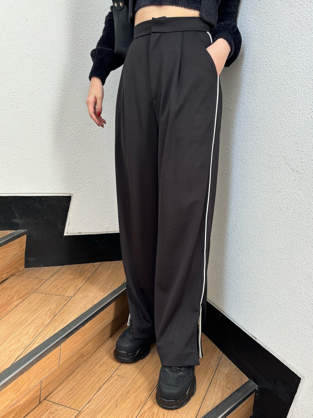 ブラック系のスラックス、ブラック系のニット/セーター、ブラック系のスニーカーを着用したレディースの冬コーディネートの5枚目の写真