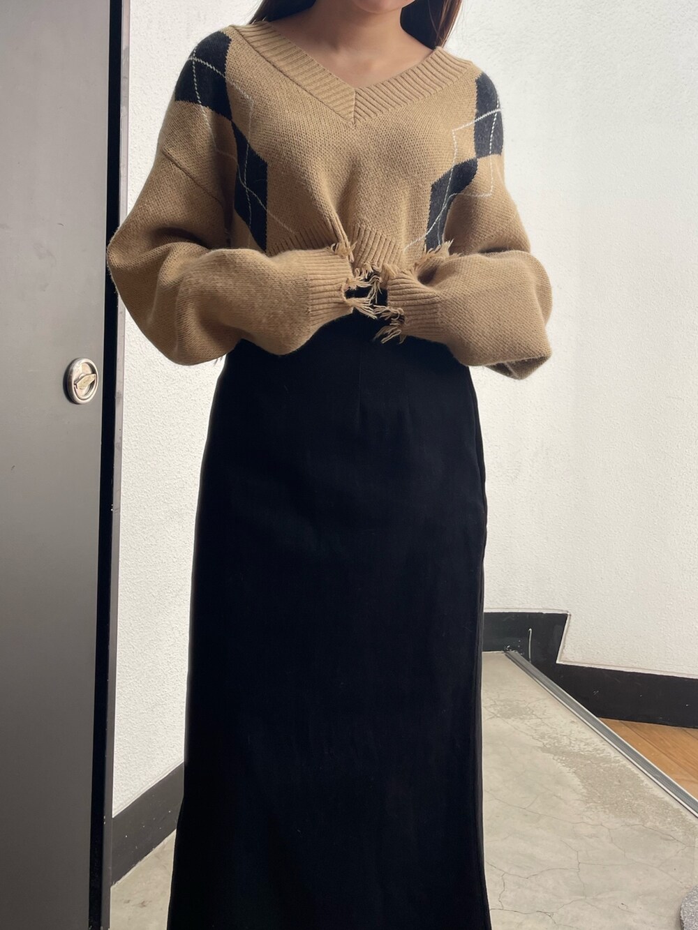 ブラック系のスカート、ブラック系のブーツ、その他のニット/セーターを着用したレディースの秋コーディネートの4枚目の写真