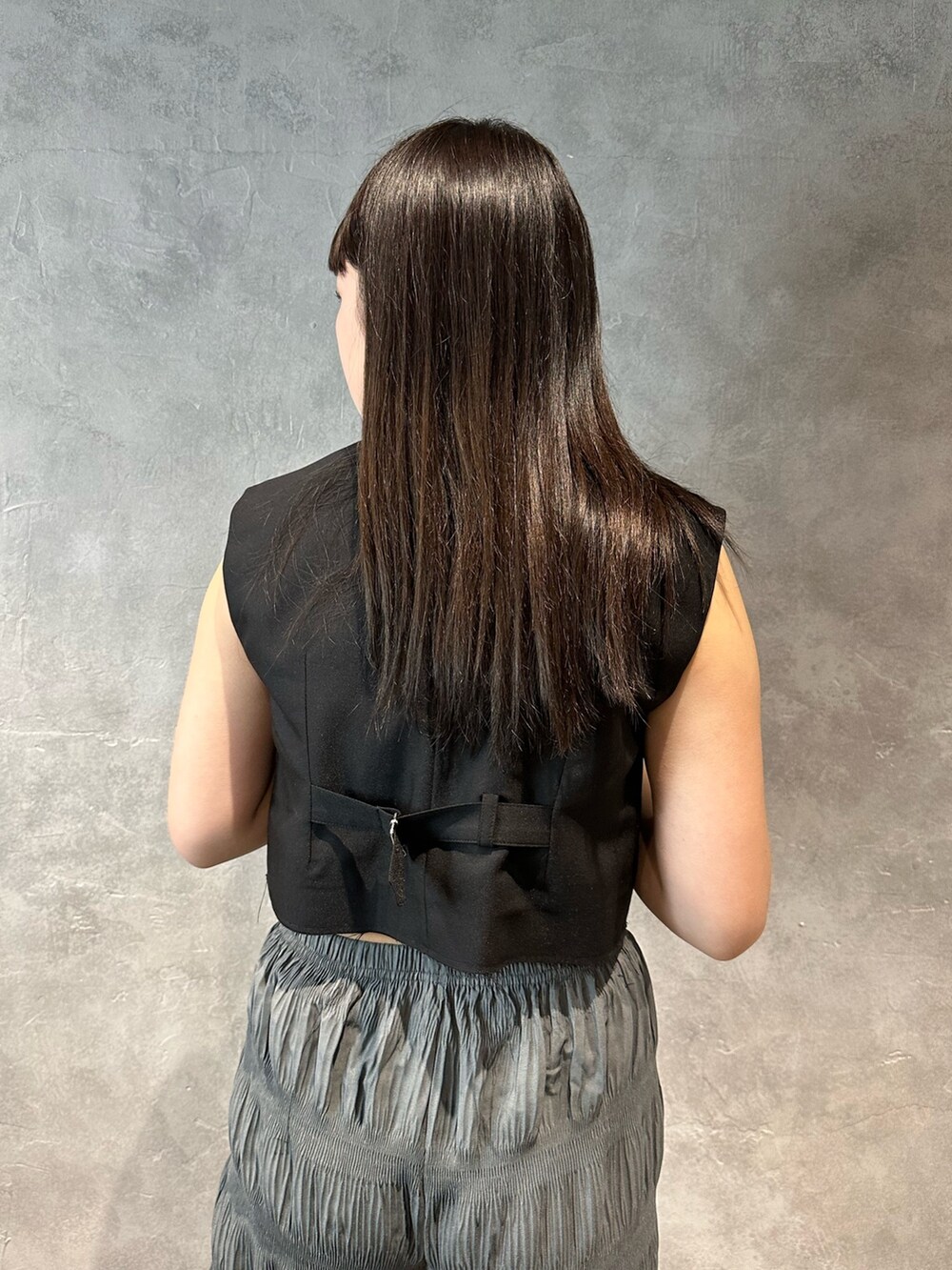 グレー系のその他パンツ、ブラック系のベスト、ブルー系のキャミソールを着用したレディースの春コーディネートの5枚目の写真