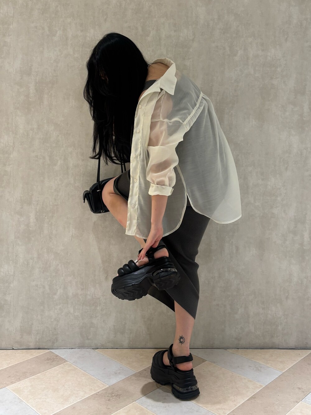 グレー系のサンダル、ブラック系のハンドバッグ、ブラック系のワンピースを着用したレディースの夏コーディネートの6枚目の写真