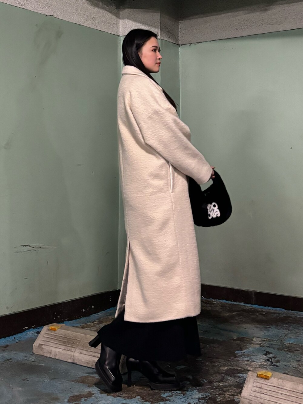 ホワイト系のチェスターコート、ブラック系のブーツ、ブラック系のハンドバッグを着用したレディースの冬コーディネートの2枚目の写真