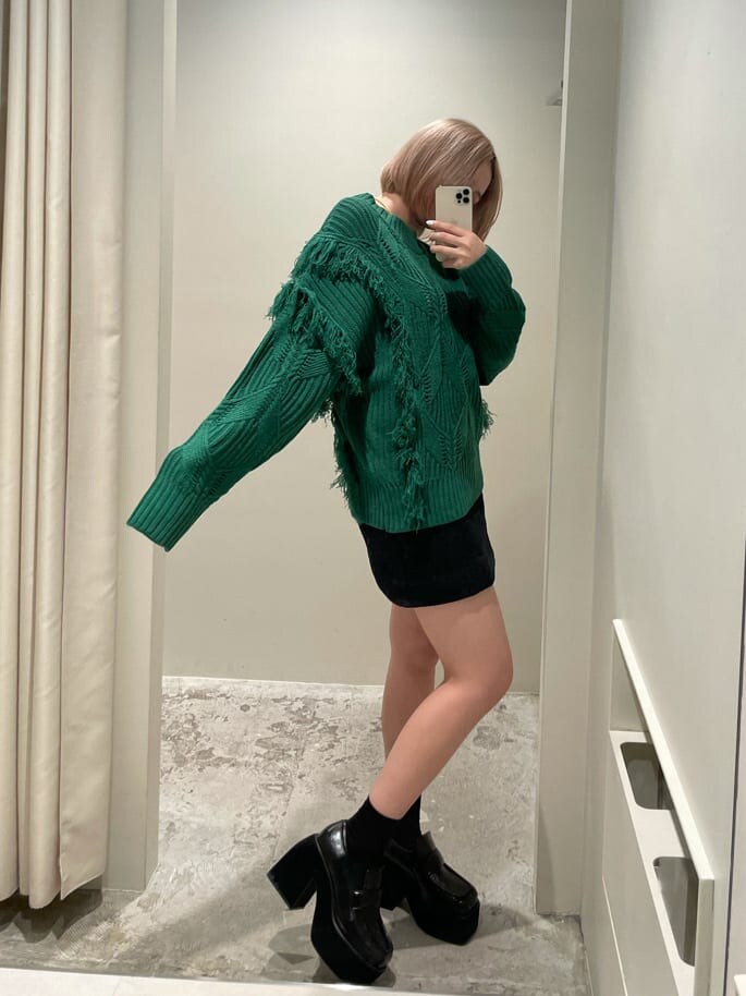 ブラック系のスカート、ブラック系のローファー、グリーン系のニット/セーターを着用したレディースの秋コーディネートの2枚目の写真