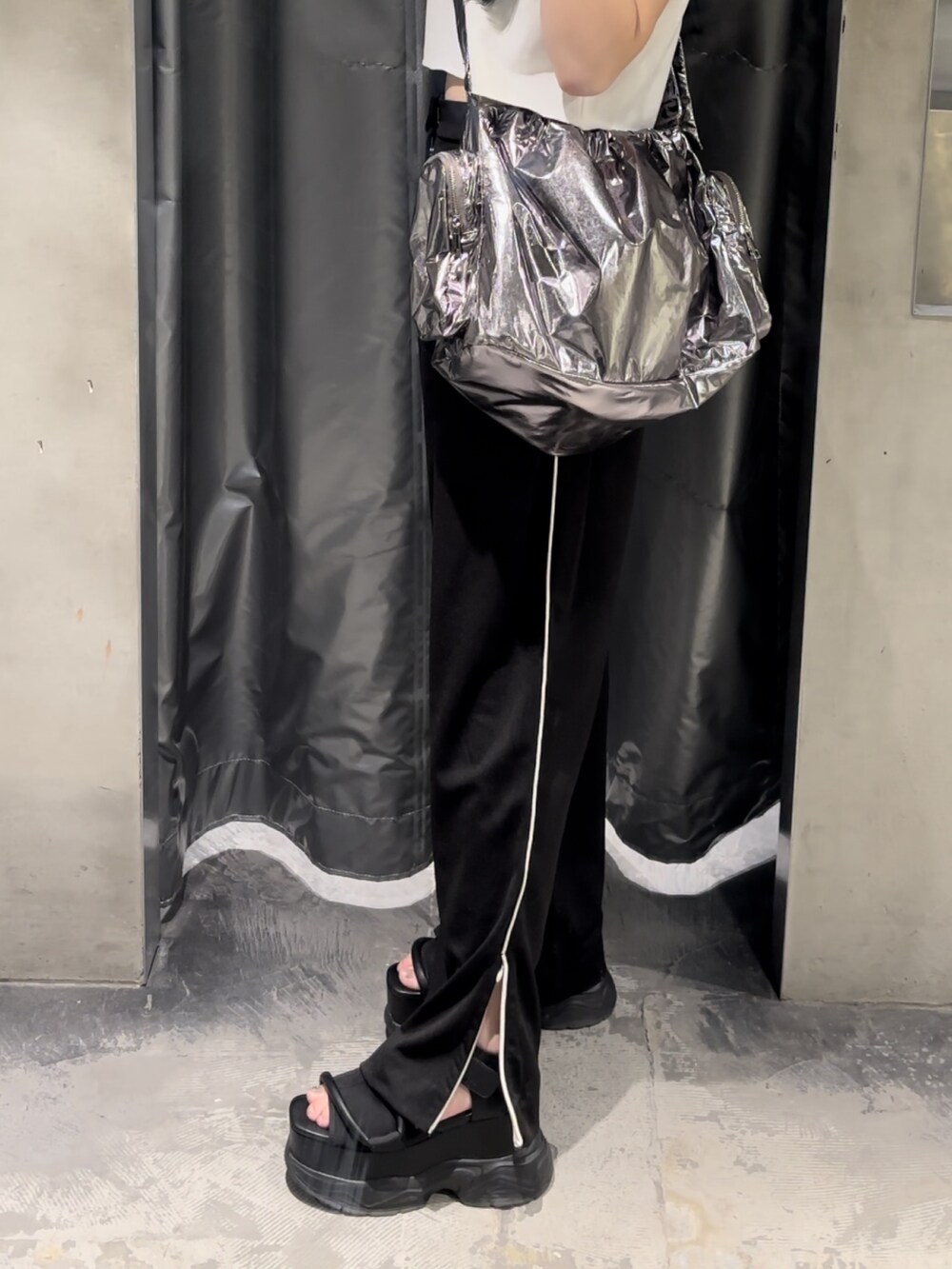 ブラック系のサンダル、ホワイト系のTシャツ/カットソー、ブラック系のスラックスを着用したレディースの夏コーディネートの5枚目の写真