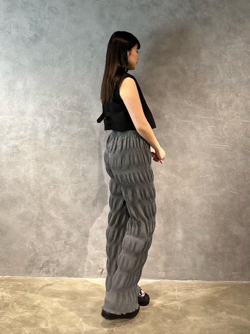 グレー系のその他パンツ、ブラック系のベスト、ブルー系のキャミソールを着用したレディースの春コーディネートの2枚目の写真