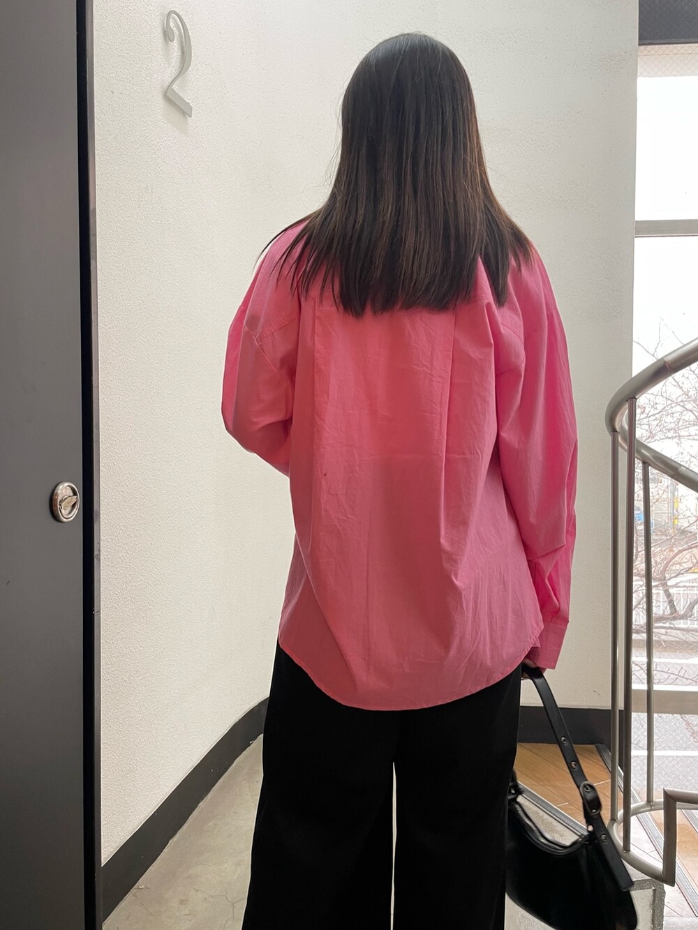 ブラック系のパンプス、ブラック系のハンドバッグ、ピンク系のシャツ/ブラウスを着用したレディースの冬コーディネートの6枚目の写真