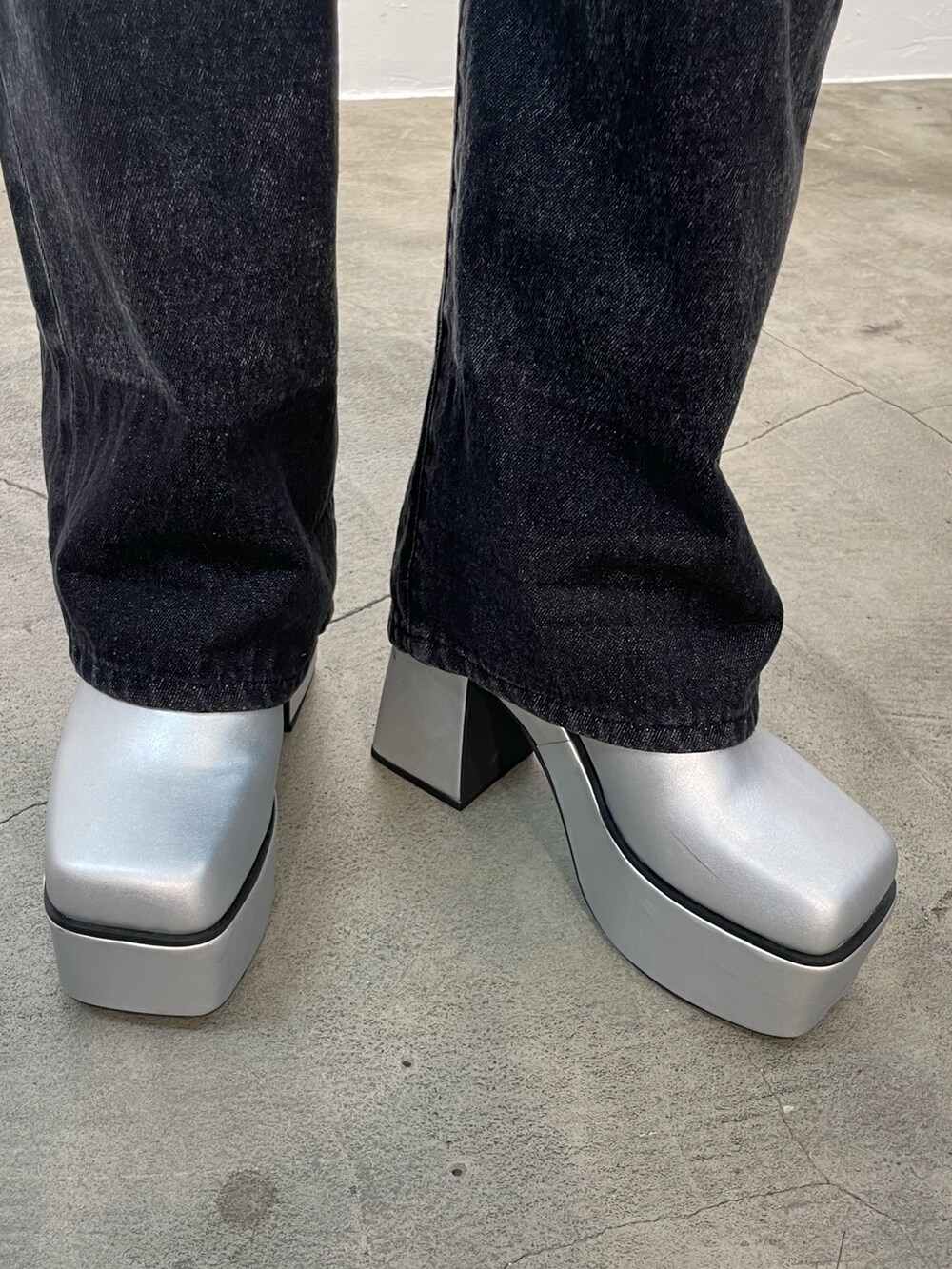 ブラック系のデニムパンツ、ブラック系のニット/セーター、シルバー系のブーツを着用したレディースの秋コーディネートの8枚目の写真