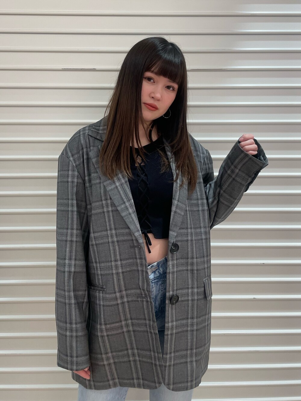 ブラック系のテーラードジャケット、ブルー系のニット/セーター、ブルー系のデニムパンツを着用したレディースの春コーディネートの4枚目の写真