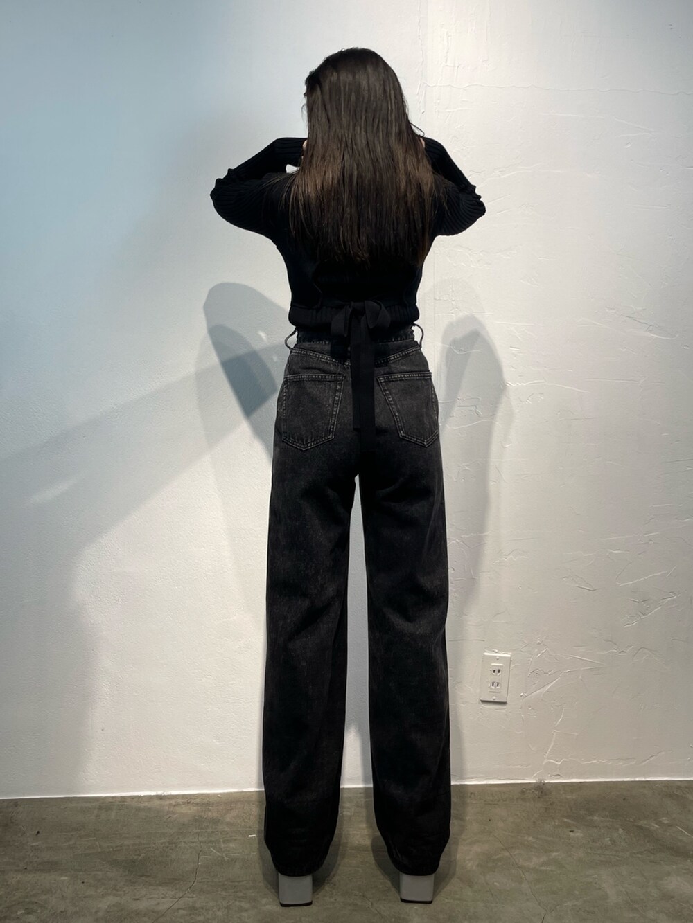 ブラック系のデニムパンツ、ブラック系のニット/セーター、シルバー系のブーツを着用したレディースの秋コーディネートの3枚目の写真