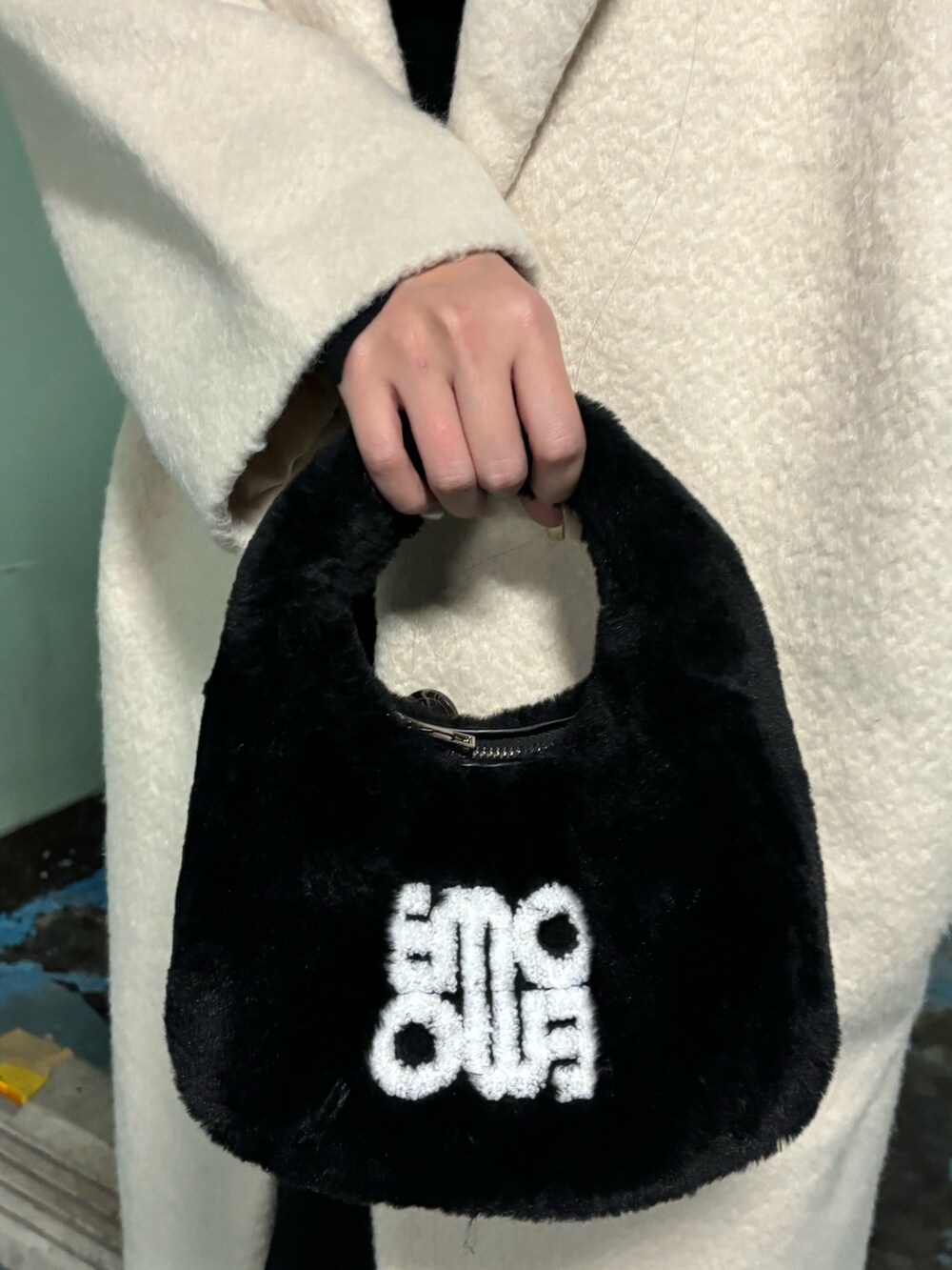 ホワイト系のチェスターコート、ブラック系のブーツ、ブラック系のハンドバッグを着用したレディースの冬コーディネートの8枚目の写真