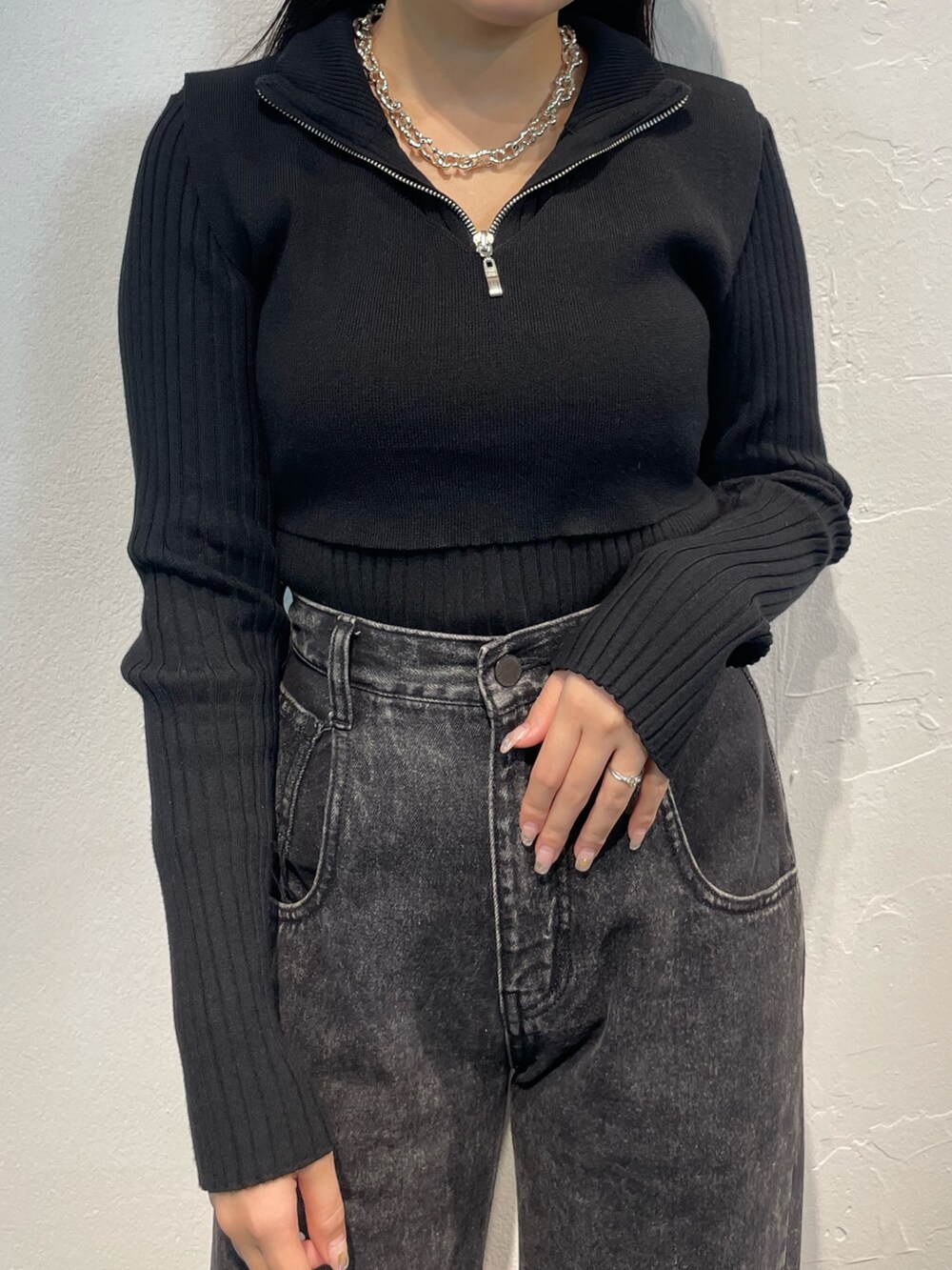 ブラック系のデニムパンツ、ブラック系のニット/セーター、シルバー系のブーツを着用したレディースの秋コーディネートの5枚目の写真