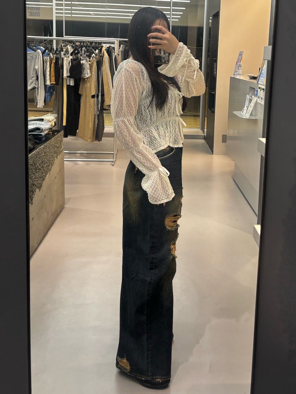 ブラック系のスニーカー、ブルー系のデニムパンツ、ホワイト系のニット/セーターを着用したレディースの春コーディネートの2枚目の写真