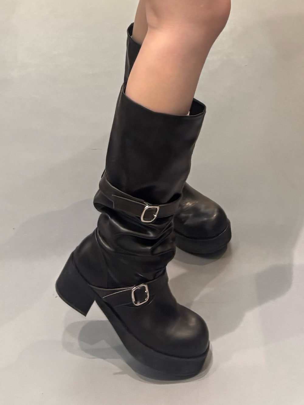 ブラック系のブーツ、ブルー系のスカート、ブラック系のTシャツ/カットソーを着用したレディースの冬コーディネートの5枚目の写真