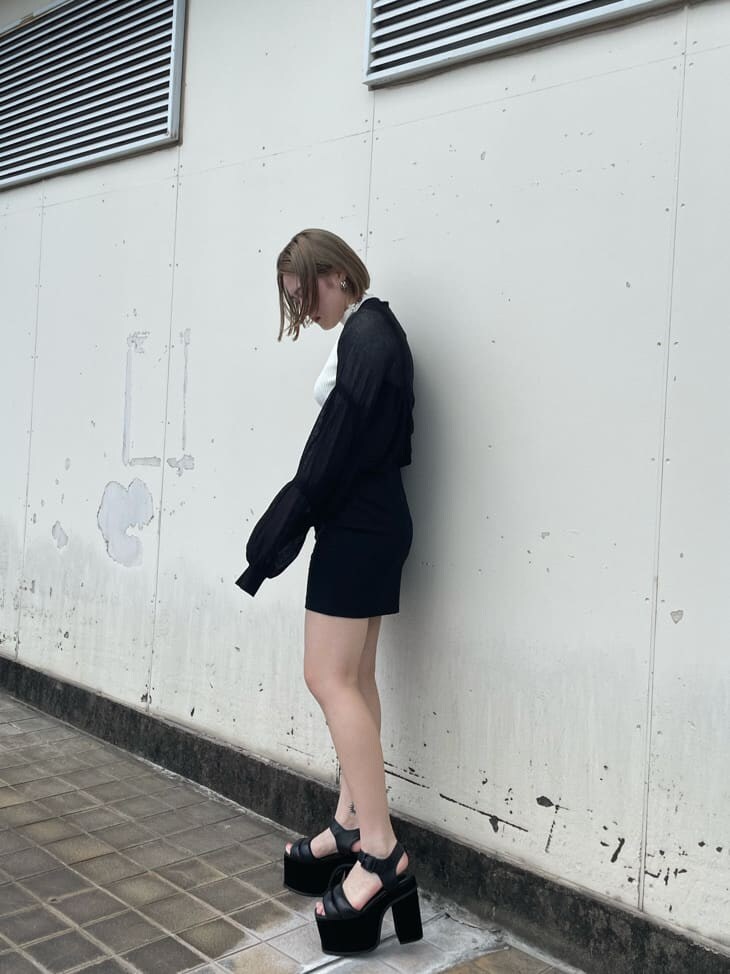 ブラック系のスカート、ブラック系のサンダル、ホワイト系のニット/セーターを着用したレディースの秋コーディネートの2枚目の写真