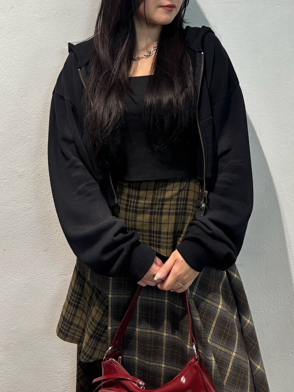 ブラウン系のブーツ、グリーン系のスカート、ブラック系のパーカーを着用したレディースの秋コーディネートの5枚目の写真