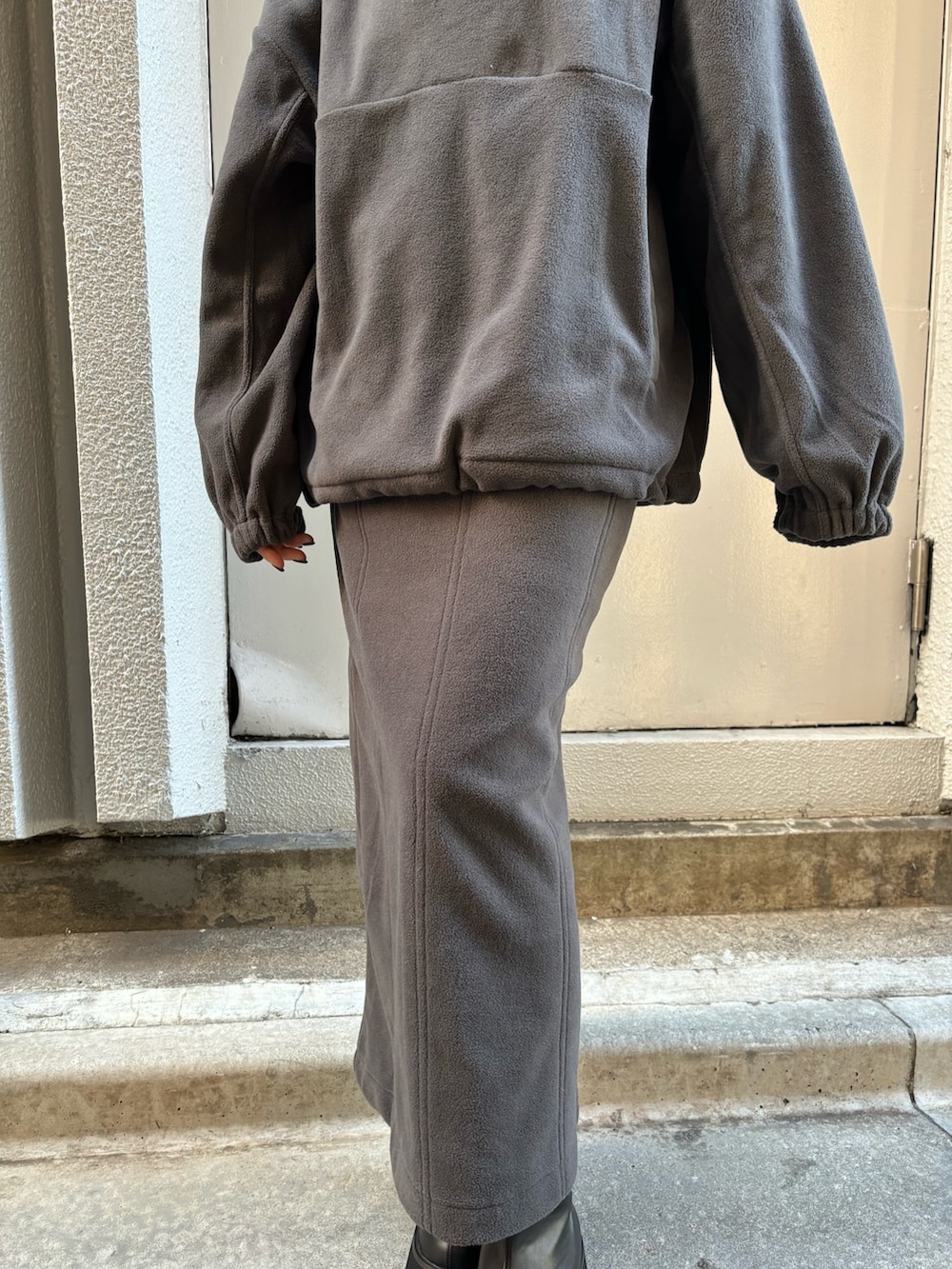 グレー系のTシャツ/カットソー、グレー系のスカート、ブラック系のブーツを着用したレディースの秋コーディネートの6枚目の写真