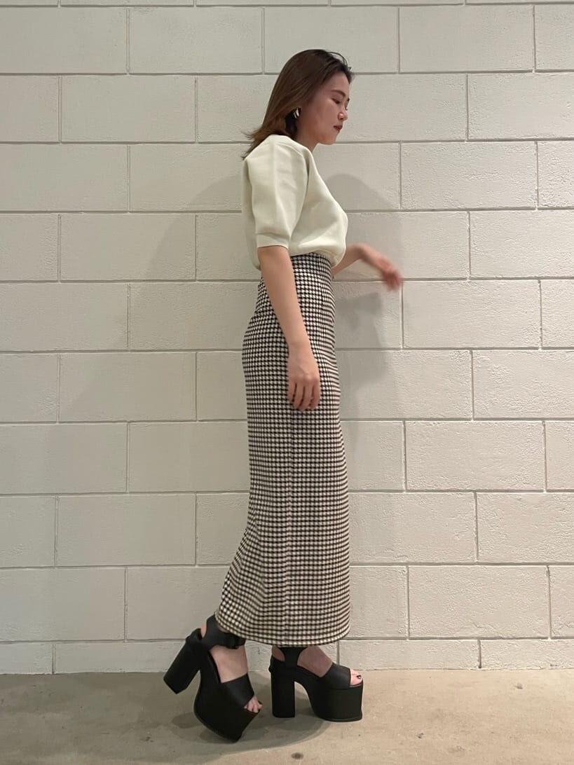 ブラック系のサンダル、ホワイト系のニット/セーター、その他のスカートを着用したレディースの春コーディネートの2枚目の写真