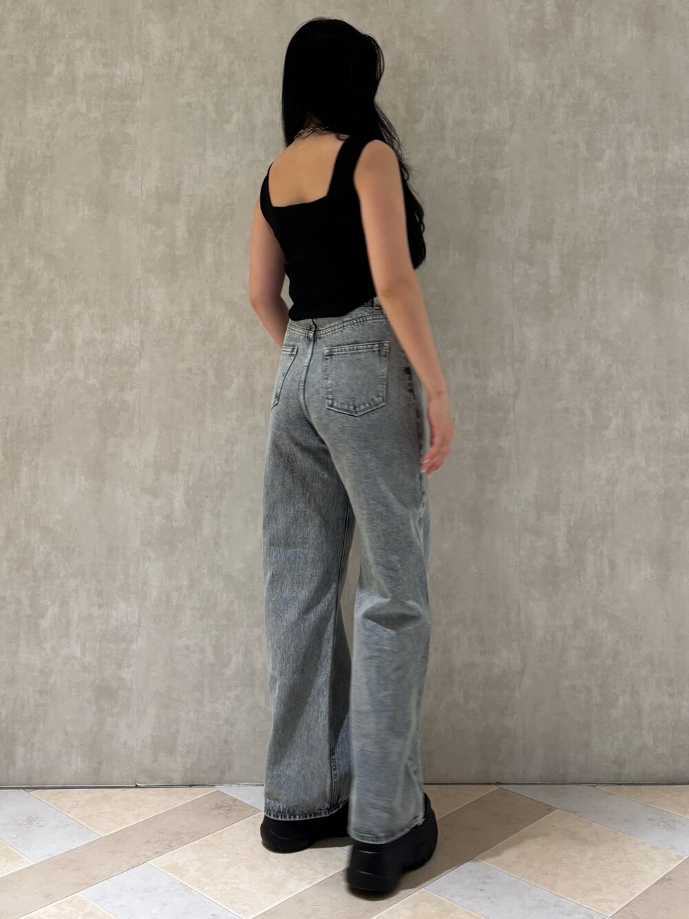 ブラック系のスニーカー、ブルー系のデニムパンツ、ブラック系のニット/セーターを着用したレディースの夏コーディネートの3枚目の写真