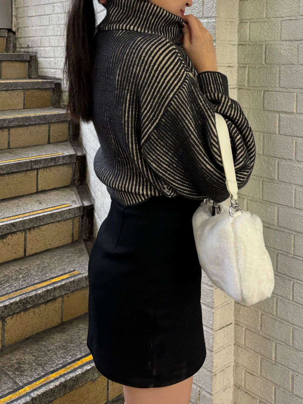 ブラック系のニット/セーター、ブラック系のスカート、その他のブーツを着用したレディースの秋コーディネートの5枚目の写真