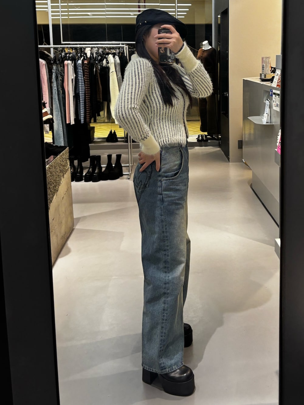 ブルー系のデニムパンツ、ブラック系のニット/セーター、ブラック系のブーツを着用したレディースの冬コーディネートの2枚目の写真