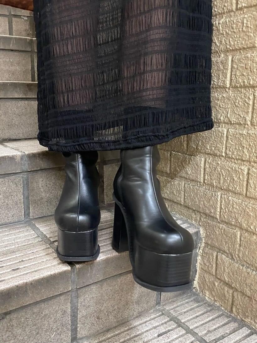 ブラック系のブーツ、ブラック系のワンピース、シルバー系のネックレスを着用したレディースの秋コーディネートの6枚目の写真