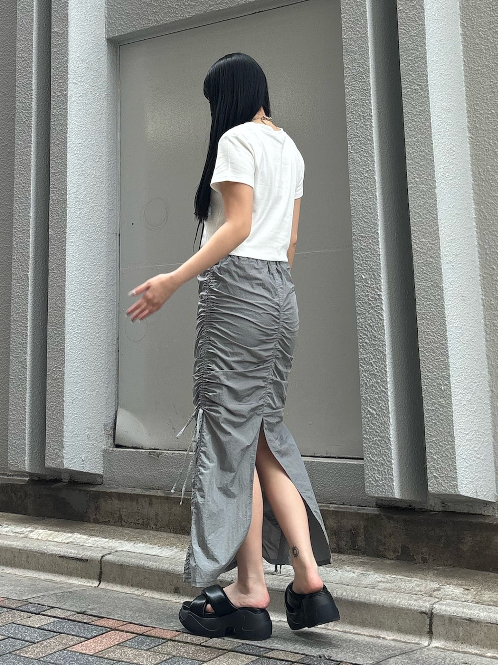 ブラック系のサンダル、ホワイト系のTシャツ/カットソー、ブラック系のハンドバッグを着用したレディースの夏コーディネートの3枚目の写真