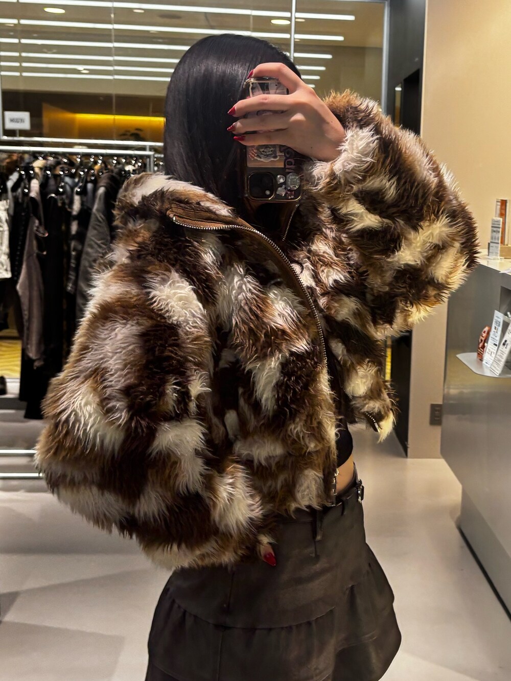 ブラック系のスカート、ブラック系のブーツ、ブラウン系のブルゾンを着用したレディースの秋コーディネートの4枚目の写真