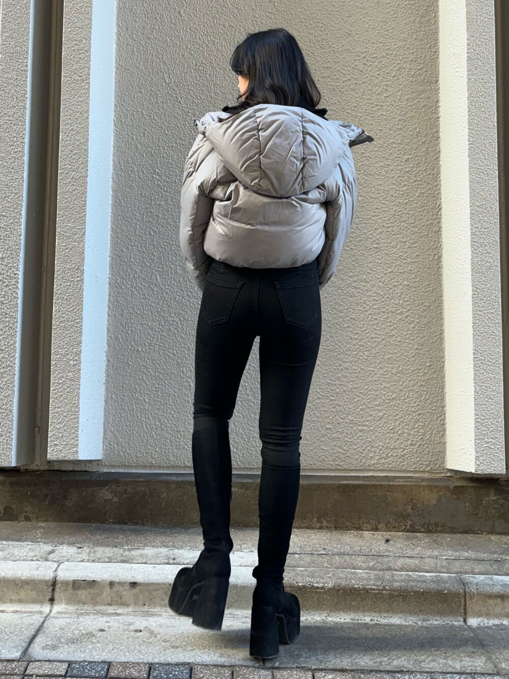 ブルー系のニット/セーター、グレー系のダウンジャケット/コート、ブラック系のデニムパンツを着用したレディースの冬コーディネートの3枚目の写真