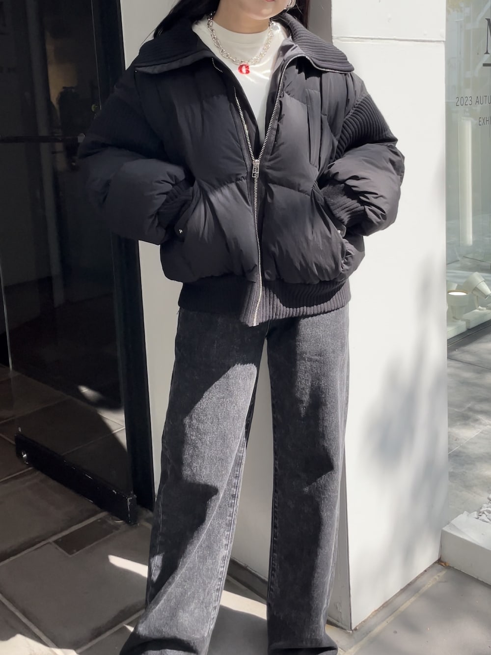 ブラック系のデニムパンツ、ブラック系のブーツ、ホワイト系のTシャツ/カットソーを着用したレディースの秋コーディネートの2枚目の写真