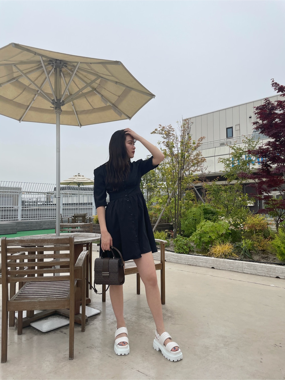 ブラック系のワンピース、ホワイト系のサンダル、ホワイト系のハットを着用したレディースの春コーディネートの5枚目の写真