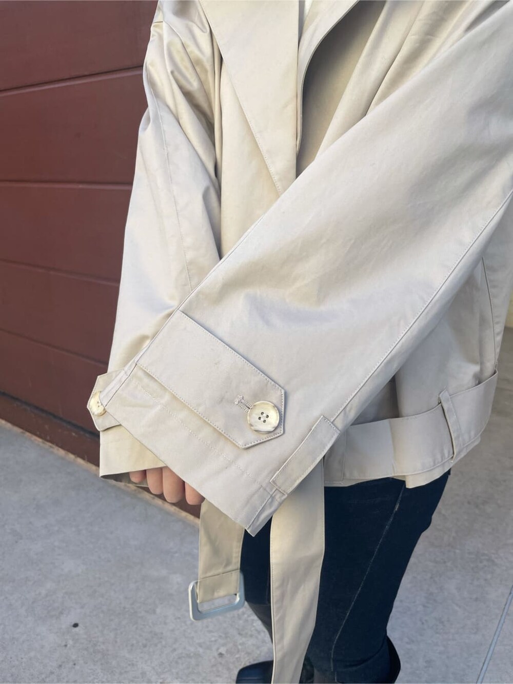 ベージュ系のトレンチコート、ブルー系のデニムパンツ、ブラック系のブーツを着用したレディースの冬コーディネートの5枚目の写真